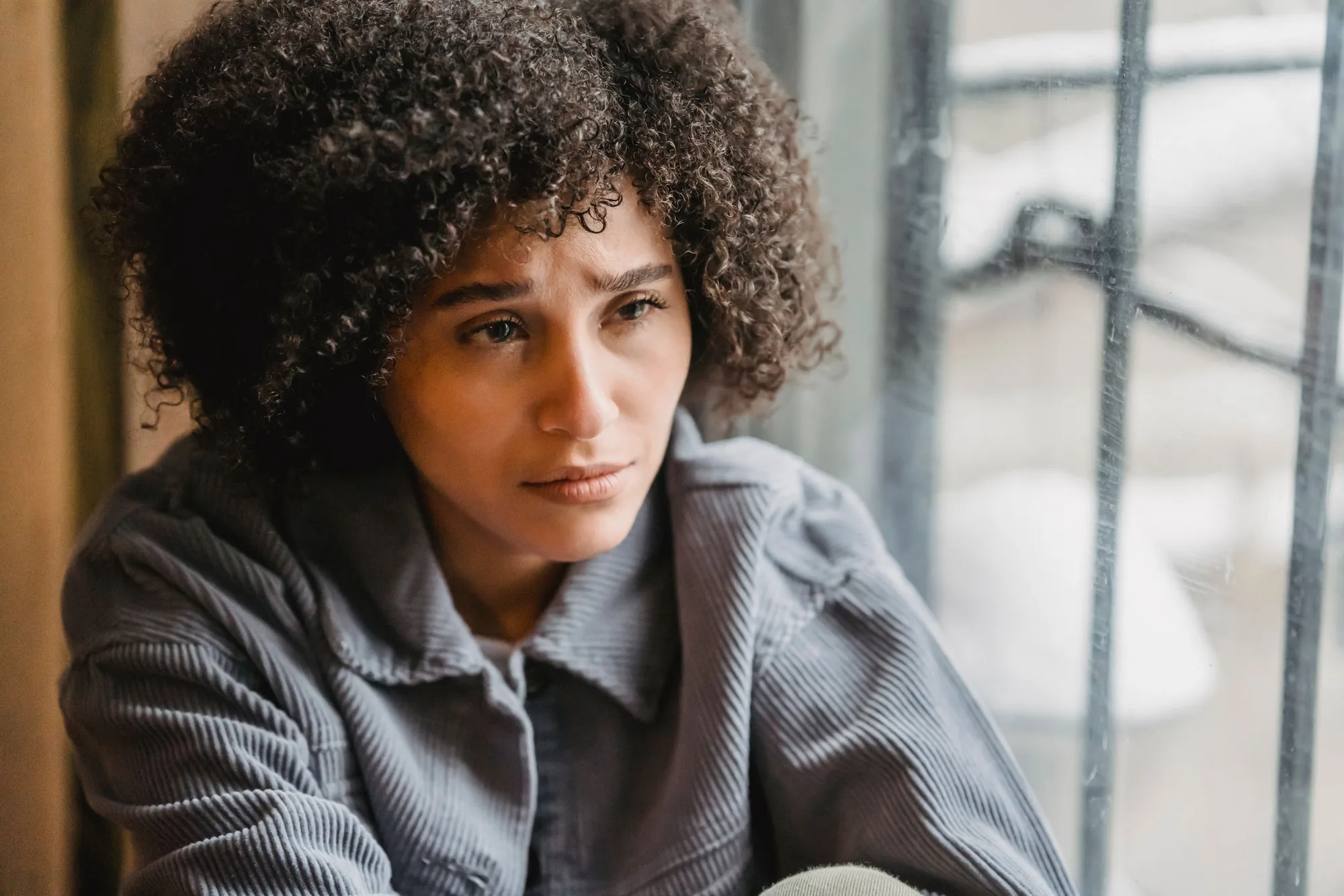 A woman sitting alone, looking worried