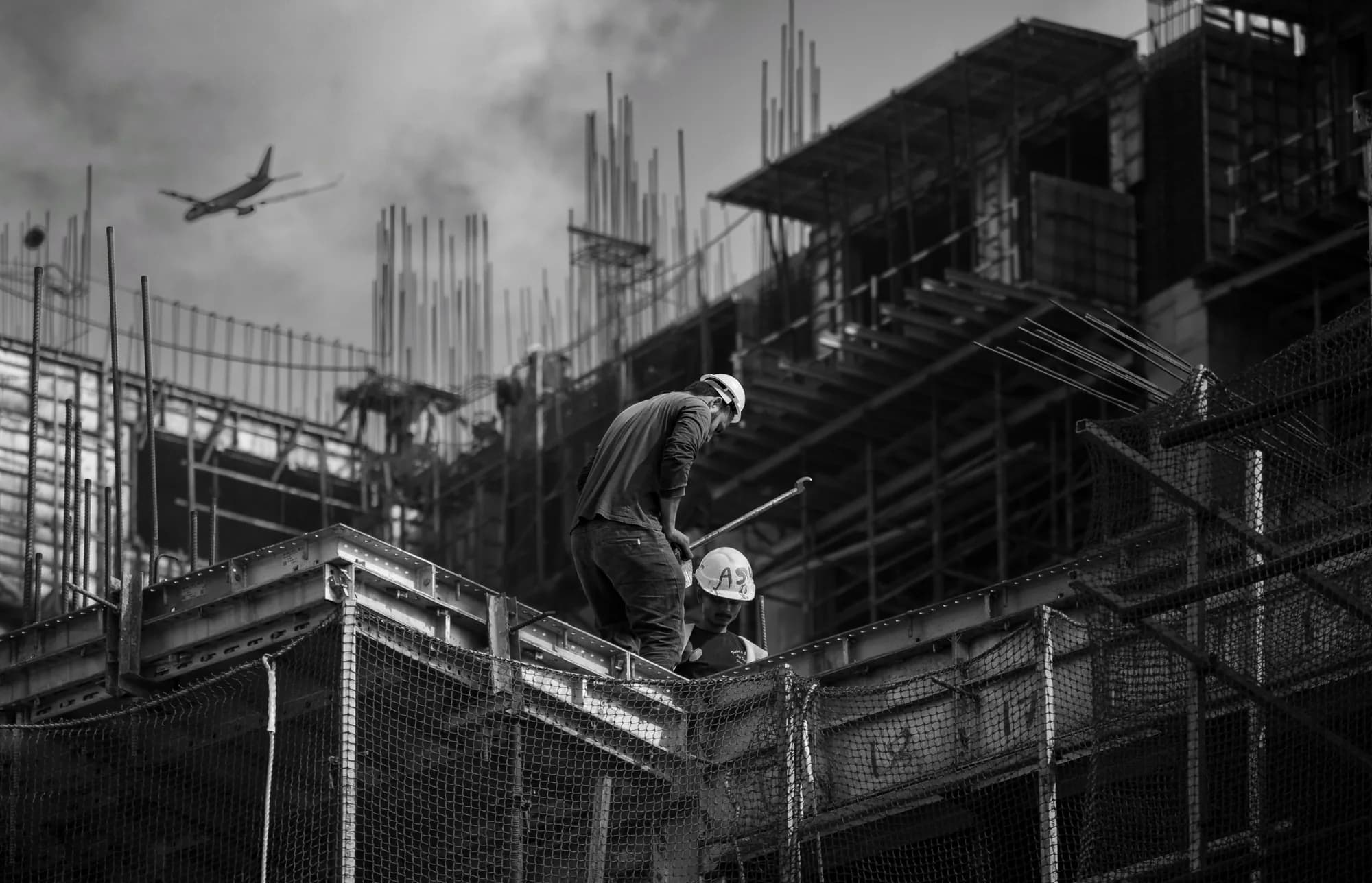 A construction worker on rebar high above a building site
